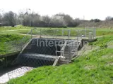 mesh safety barrier on river dam surrounded by green grass 